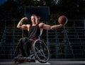 Strong basketball player in wheelchair pose with a ball on open gaming ground. Royalty Free Stock Photo