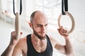 Strong bearded athlete with wireless headphone holding crosstraining rings at crossfit hall Royalty Free Stock Photo