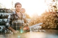 Strong bearded woodcutter wearing plaid shirt hold chainsaw in hand on background of sawmill