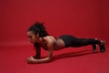 Strong beautiful young african american sports fitness woman in sportswear working out  on red background studio Royalty Free Stock Photo