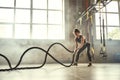 Strong and beautiful. Young athletic woman with perfect body doing crossfit exercises with a rope in the gym. Royalty Free Stock Photo