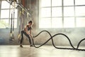 Strong and beautiful. Young athletic woman with perfect body doing crossfit exercises with a rope in the gym. Royalty Free Stock Photo