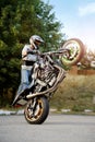 Strong biker showing extreme stunt on one wheel.