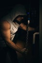 A strong bodybuilder makes triceps exercises with a chain in the gym.