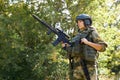 Strong brave female army soldier with rifle machine gun standing in the forest