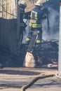 A strong and brave fireman rescues a burning building using water in a fire operation. Fireman in a fire protection suit.