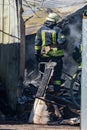 A strong and brave fireman rescues a burning building using water in a fire operation. Fireman in a fire protection suit.