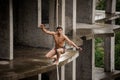 Strong brave topless man balancing on a slackline on rainy day