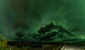 Strong bright Aurora Borealis behind heavy clouds over road, Joesjo Lake and Scandinavian mountains in Swedish Lapland Lake look Royalty Free Stock Photo