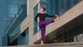 Strong calm woman muslim islamic girl in hijab barefoot lady in purple pants stands city building background bending