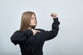 Strong caucasian young woman showing muscules, pointing finger on it.