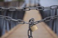 Strong chain with padlock blocks the way to a wooden bridge. Close up image