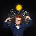 Strong child boy with lightbulb on blackboard background. Brainstorming and idea concept Royalty Free Stock Photo