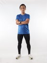 Strong confidence athletic young Asian male wearing running jersey looking at camera with crossed arms, full length studio shot