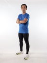 Strong confidence athletic young Asian male wearing running jersey looking at camera with crossed arms, full length studio shot