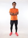 Strong confidence athletic young Asian male wearing running jersey looking at camera with crossed arms, full length studio shot Royalty Free Stock Photo