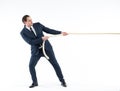 Strong and confident business leader. Side view of businessman in suit pulling a rope while standing against white