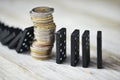 Strong currency or economy concept with pile of coins stopping the fall of black domino blocks Royalty Free Stock Photo