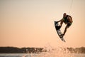 energy muscular sportsman making trick in jump time with wakeboard against the backdrop of the sky Royalty Free Stock Photo