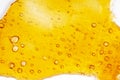 Strong extract of gold cannabis wax with high thc close up, bubble shatter texture on paper