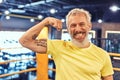Portrait of a happy handsome mature man showing his biceps and smiling at camera while standing on the boxing ring at Royalty Free Stock Photo