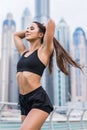 Strong fit female athlete getting ready for workout towards the skyscrapers. Strong fitness woman tying ponytail. Motivation and Royalty Free Stock Photo