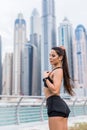 Strong fit female athlete getting ready for workout towards the skyscrapers. Strong fitness woman tying ponytail. Motivation and Royalty Free Stock Photo