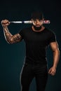 Strong and fit man bodybuilder with baseball bat in black t-shirt. Sporty muscular guy athlete. Sport and fitness Royalty Free Stock Photo