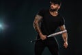 Strong and fit man bodybuilder with baseball bat in black t-shirt. Sporty muscular guy athlete. Sport and fitness Royalty Free Stock Photo