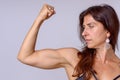 Strong fit mature woman flexing her arm muscles