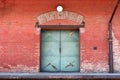 Strong rusted metal doors on red brick building connected to trucks unloading bay