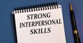 STRONG INTERPERSONAL SKILLS - words in a white notebook on a blue background with a pen