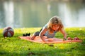 Strong kid push up exercise on the roll mat in the park outdoor. Athletic boy is pushing up on the green grass. Royalty Free Stock Photo