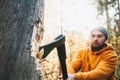 Strong logger worker cuts tree in forest. Ax close up, blurred lumberjack on background