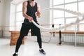 Strong male athlete doing exercises with rope at crossfit gym