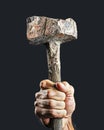 Strong male hand holding a rough primitive hammer made of angular stone against a dark background Royalty Free Stock Photo