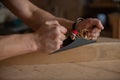 Strong male hands hold a plane and process a piece of wood with it. Royalty Free Stock Photo