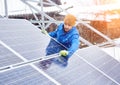 Strong male technician in blue suit installing photovoltaic blue solar modules as renewable energy source. Royalty Free Stock Photo