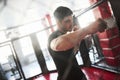 Strong man is boxing in the gym behind the fence. Haves daily exercise