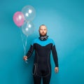 Strong man diver with birthday balloon making funny face on blue background Royalty Free Stock Photo
