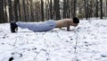 Strong man doing push ups on snow at winter forest. Sportsman exercising at nature. Young guy training outdoor. Muscular Royalty Free Stock Photo