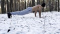 Strong man doing push ups on snow at winter forest. Sportsman exercising at nature. Young guy training outdoor. Muscular Royalty Free Stock Photo