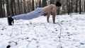 Strong man doing push ups on snow at winter forest. Sportsman exercising at nature. Young guy training outdoor. Muscular Royalty Free Stock Photo