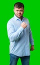 A strong man with fists raised, smiling confidently, on a bright green background Royalty Free Stock Photo