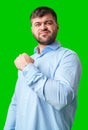 A strong man with fists raised, smiling confidently, on a bright green background Royalty Free Stock Photo