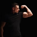 Strong man looking and showing her biceps arm on dark black background Royalty Free Stock Photo