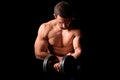 Strong man with muscular body working out. Weight exercise with dumbbell on black background. Royalty Free Stock Photo