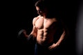 Strong man with muscular body working out. Weight exercise with dumbbell on black background. Royalty Free Stock Photo