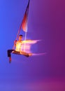 Strong man, professional aerial gymnast, acrobat training with aerial tissues against gradient blue purple studio