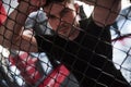 Strong man. Sportive guy in black shirt stands behind the fence in the room with daylight behind